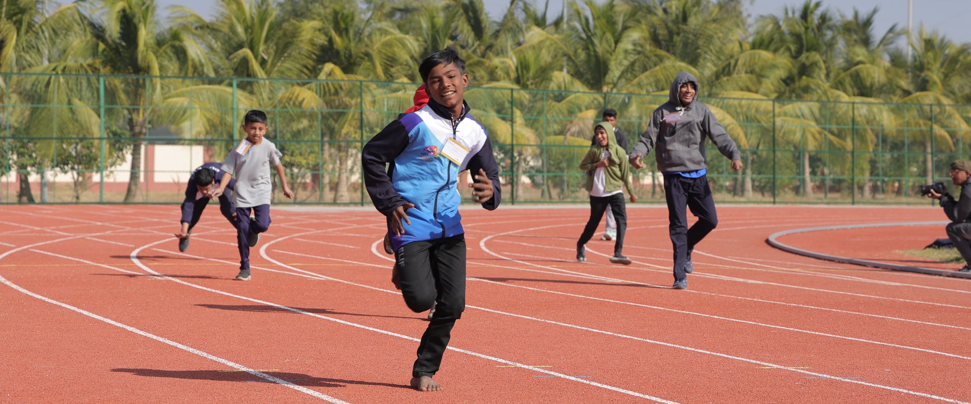A smiling young athlete running towards the camera at the Special Khel Mahakumbh 2025 state-level competition, Porbandar